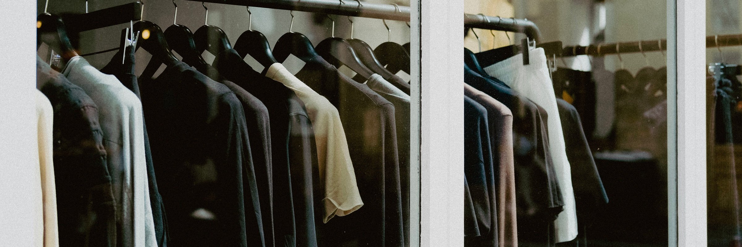Roupas em cabides dentro de vitrine de loja de moda.