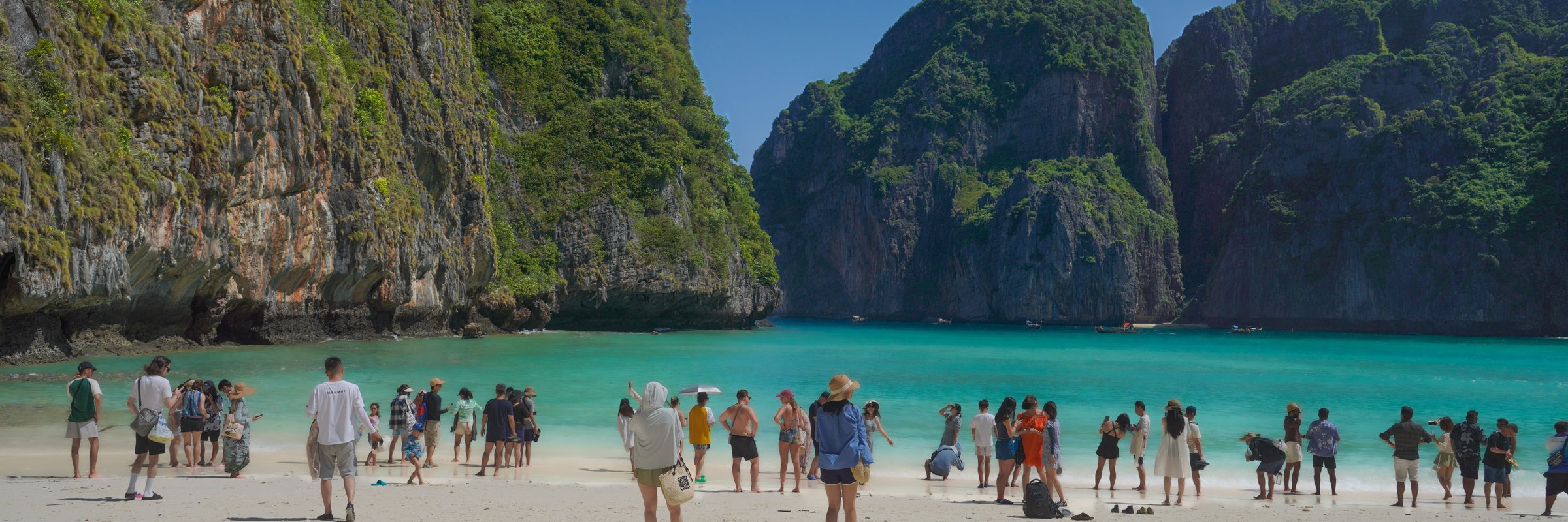 Praia de Maya Bay na Tailândia, cercada por falésias e águas turquesa.